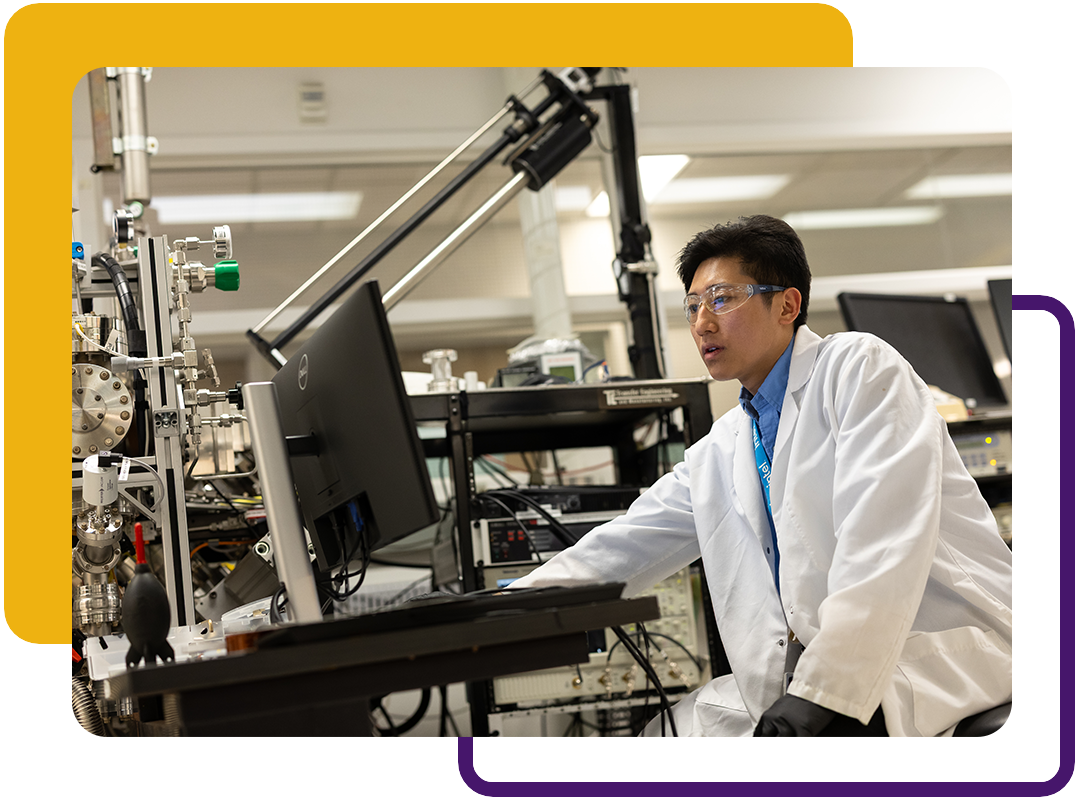 A student in a lab coat working on a computer.